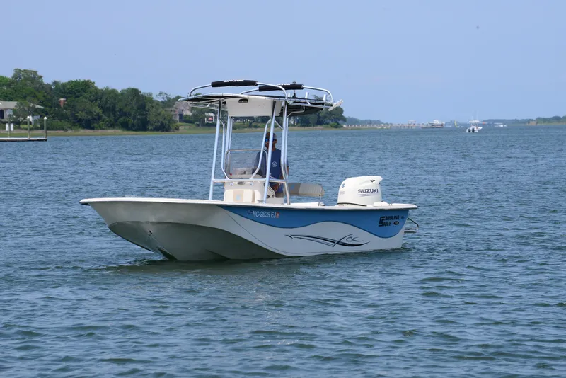 Slide: The Image of 2018 Carolina Skiff 218 DLV boat on calm water with Suzuki outboard motor. - 3