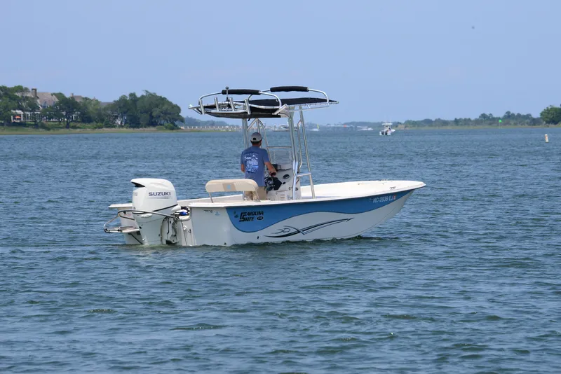 Slide: The Image of 2018 Carolina Skiff 218 DLV boat on calm water with person steering. - 8