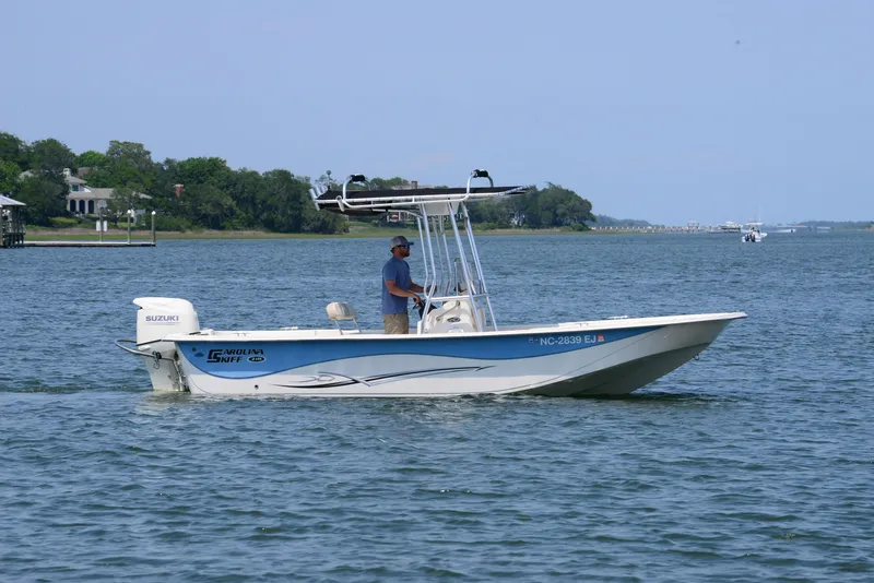 Slide: The Image of 2018 Carolina Skiff 218 DLV boat cruising on a calm lake with a person steering. - 9