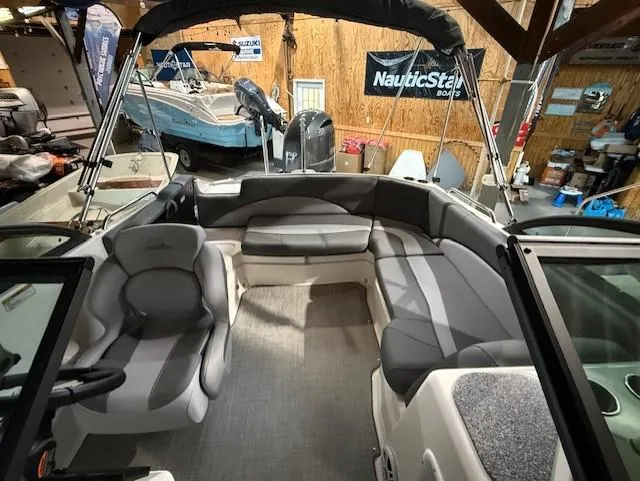 Slide: The Image of 2023 NauticStar 203 DC boat interior with gray seating and canopy in showroom. - 9