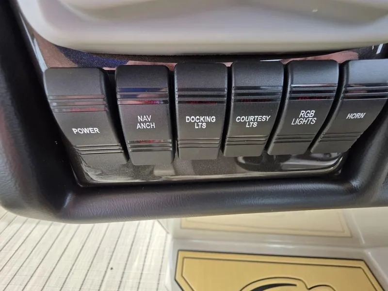 Slide: The Image of Control panel switches on a 2025 Veranda VR22RC Tri-Toon boat dashboard. - 39
