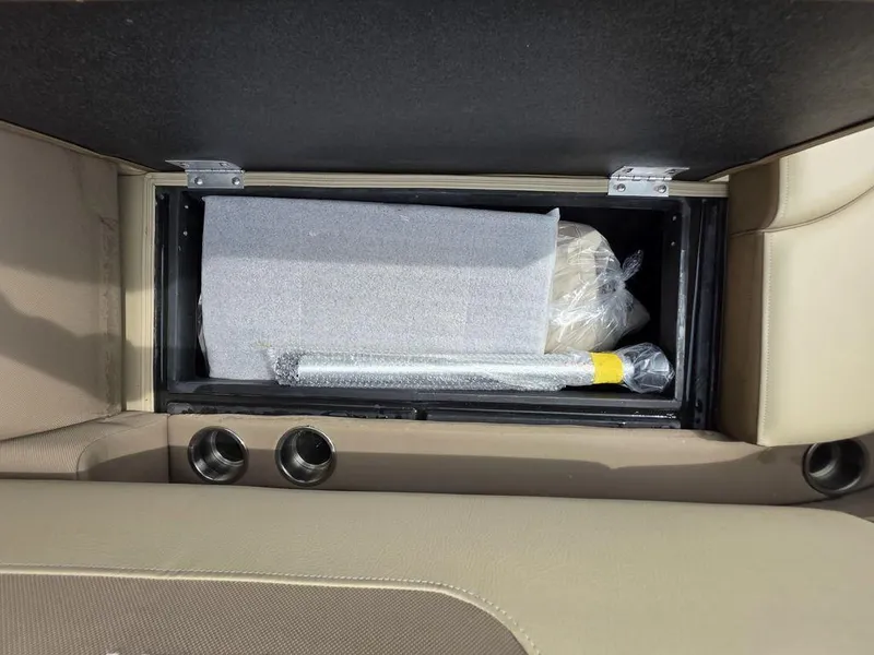 Slide: The Image of Storage compartment in 2025 Veranda VR22RC Tri-Toon boat, featuring beige upholstery and cup holders. - 42