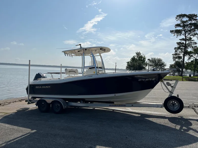 Slide: The Image of 2011 Sea Hunt Ultra 232 boat on trailer by a lakeside. - 0