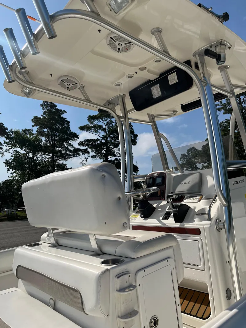 Slide: The Image of 2011 Sea Hunt Ultra 232 boat interior with helm and seating, under a clear blue sky. - 16