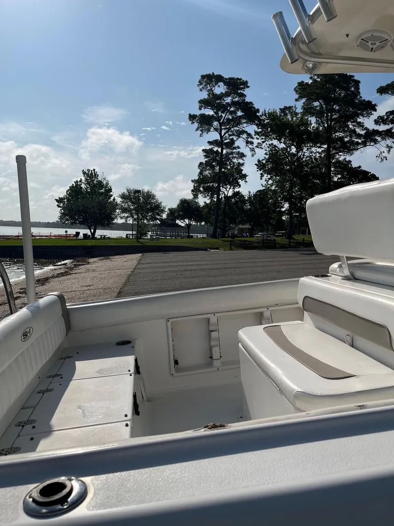 Slide: The Image of 2011 Sea Hunt Ultra 232 boat interior with seating, docked near a scenic waterfront. - 17