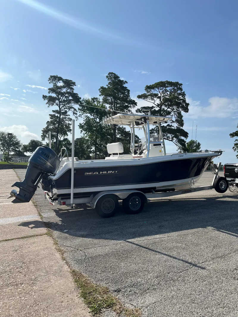 Slide: The Image of 2011 Sea Hunt Ultra 232 boat on trailer, parked outdoors under clear sky. - 2