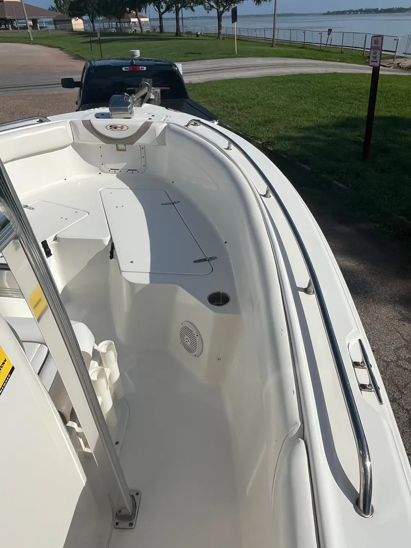 Slide: The Image of 2011 Sea Hunt Ultra 232 boat docked near a waterfront, showcasing spacious deck design. - 33