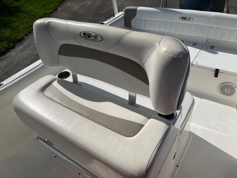 Slide: The Image of 2011 Sea Hunt Ultra 232 boat seating with cup holder, featuring white and gray upholstery. - 43