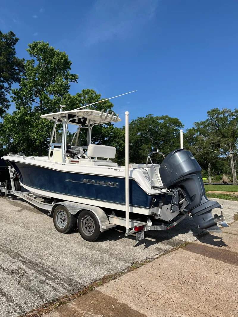 Slide: The Image of 2011 Sea Hunt Ultra 232 boat on trailer, parked outdoors under clear blue sky. - 5