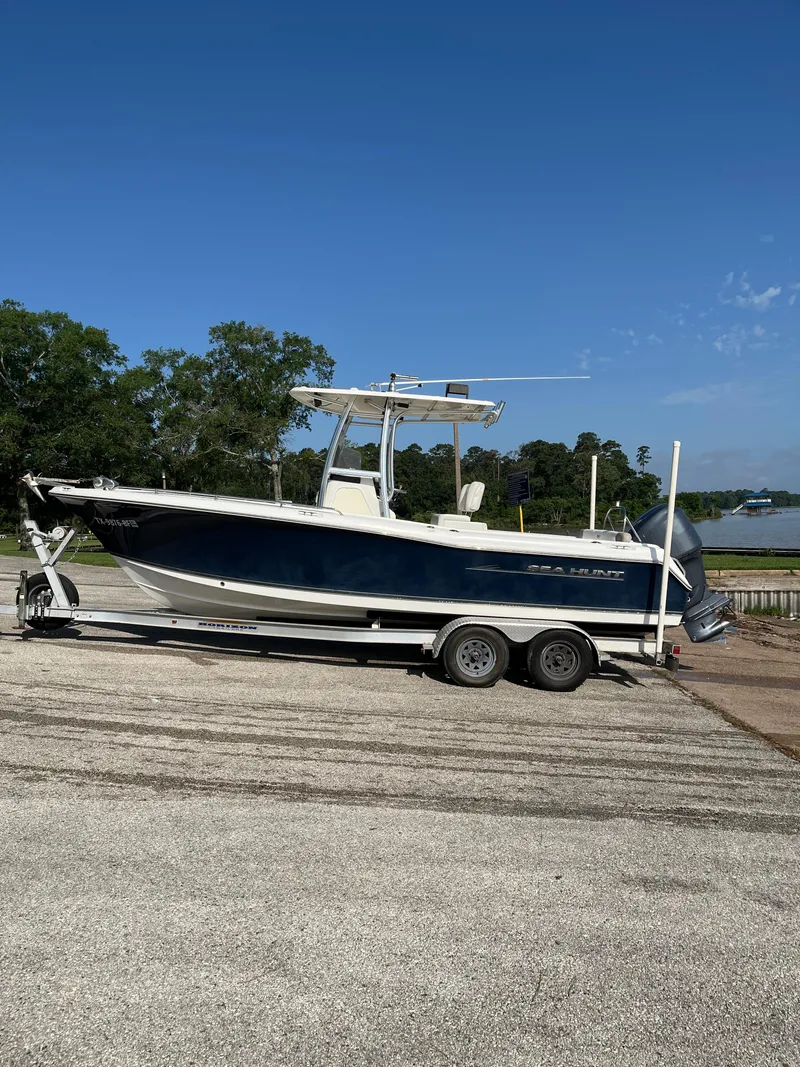 Slide: The Image of 2011 Sea Hunt Ultra 232 boat on trailer, parked outdoors under clear blue sky. - 7