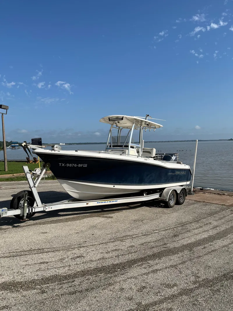Slide: The Image of 2011 Sea Hunt Ultra 232 boat on trailer by the water under a clear blue sky. - 8