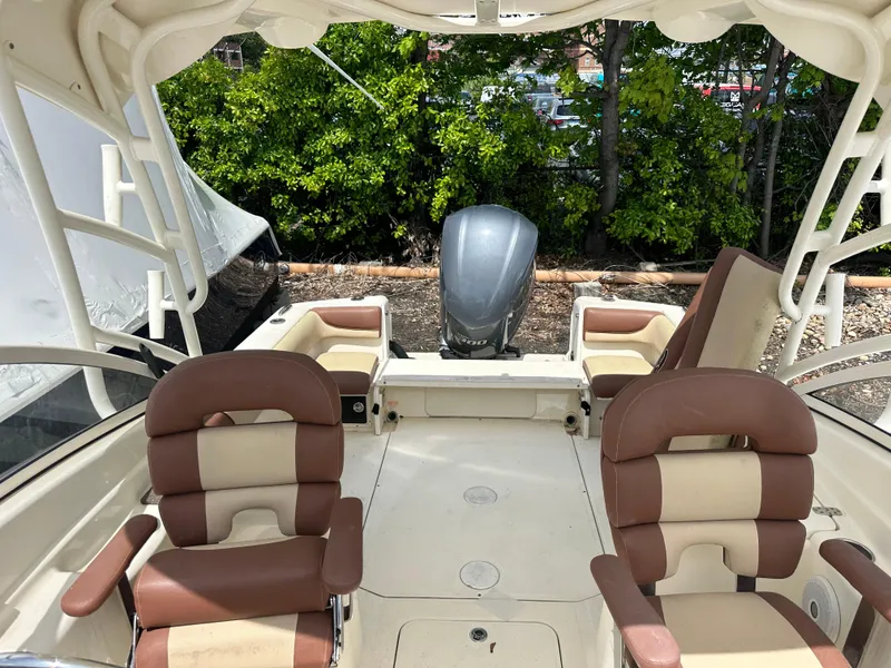 Slide: The Image of 2014 Scout 245 Dorado boat interior with seating and engine, surrounded by greenery. - 14