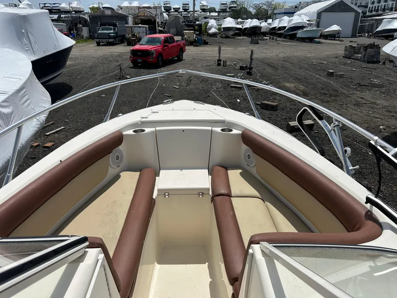 Slide: The Image of 2014 Scout 245 Dorado boat with brown seating, parked in a marina with covered boats. - 16