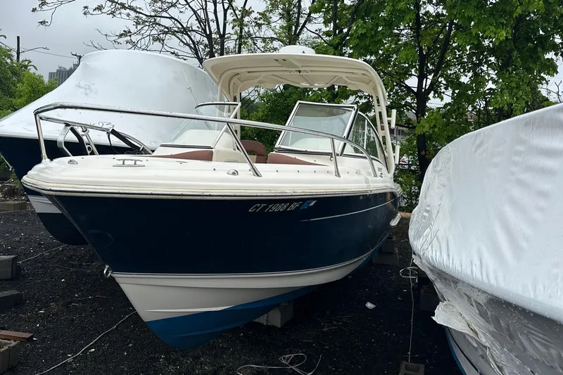 Slide: The Image of 2014 Scout 245 Dorado boat, docked outdoors, surrounded by trees and covered boats. - 5