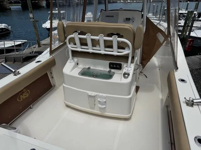 Slide: The Image of 2020 NauticStar 2602 Legacy boat interior with rod holders and seating at a marina. - 18