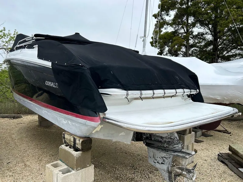 Slide: The Image of 2010 Cobalt 262 boat covered, elevated on blocks, with trees in the background. - 3