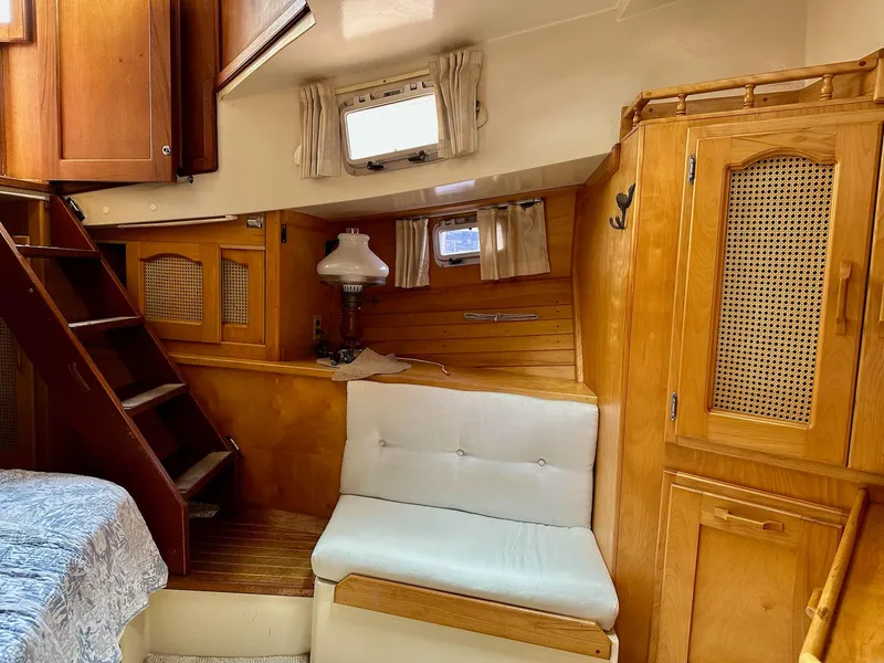 Slide: The Image of Cozy 1989 Pilgrim Trawler interior with wooden cabinetry, stairs, and a cushioned seating area. - 14