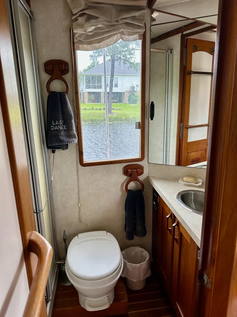Slide: The Image of Interior of 1989 Pilgrim Trawler bathroom with toilet, sink, and window view. - 15