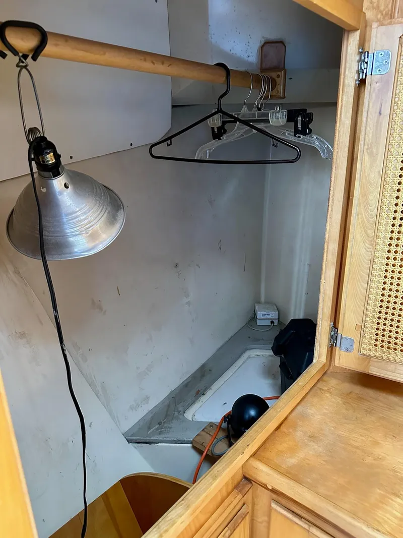 Slide: The Image of 1989 Pilgrim Trawler interior closet with hangers, lamp, and wooden cabinetry. - 21