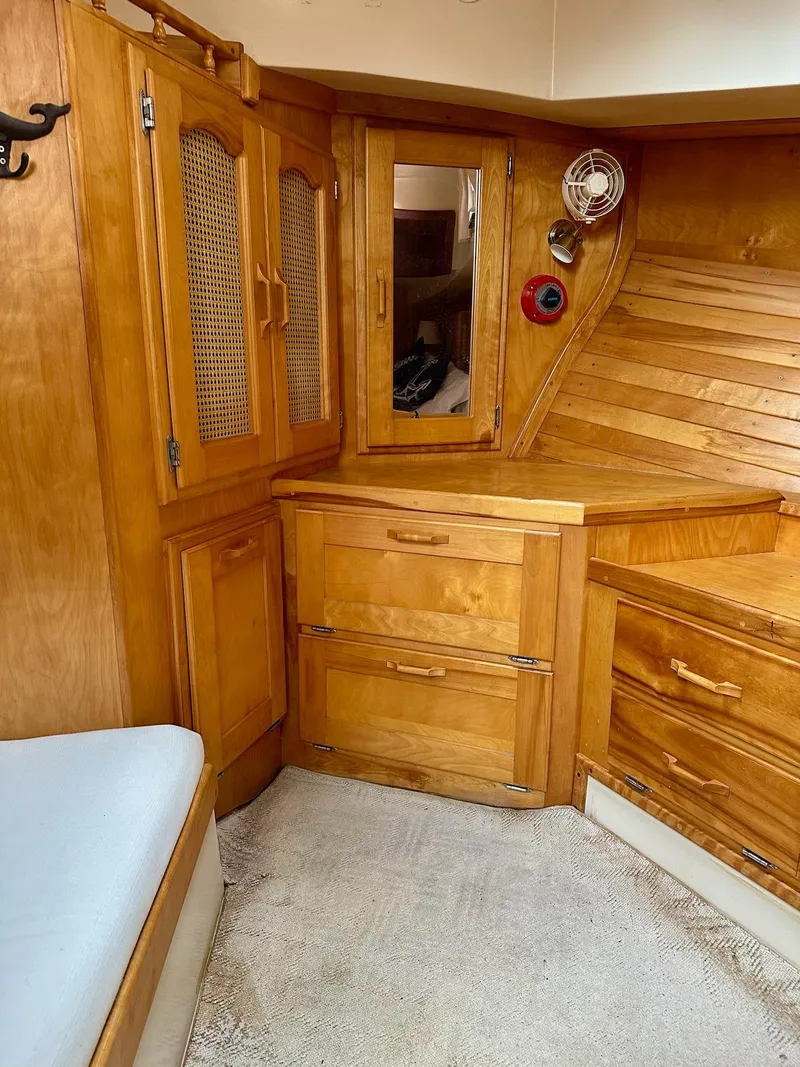 Slide: The Image of 1989 Pilgrim Trawler interior with wooden cabinetry and drawers, featuring a cozy seating area. - 22