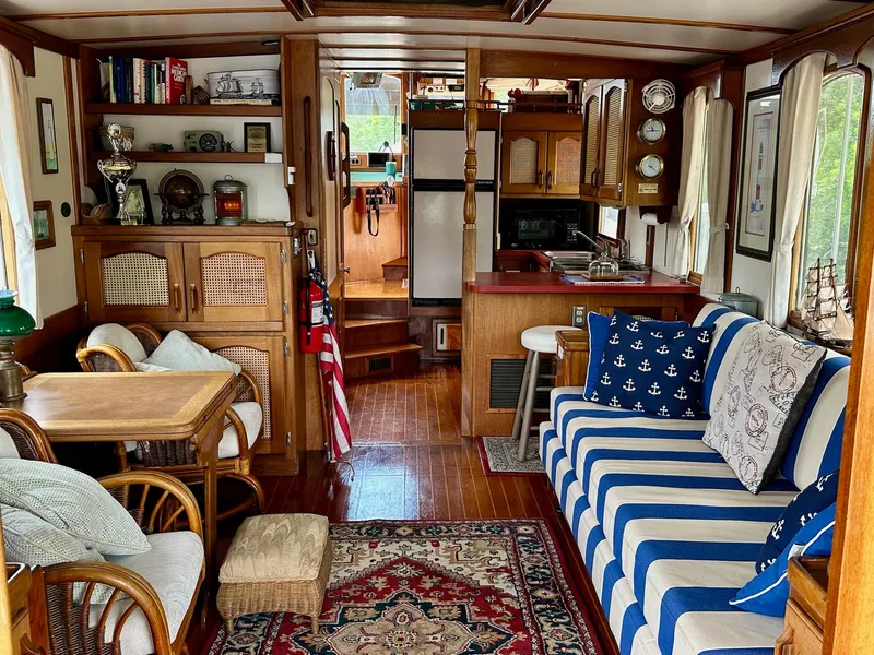 Slide: The Image of 1989 Pilgrim Trawler interior with nautical decor, striped sofa, wooden furnishings, and cozy seating area. - 31