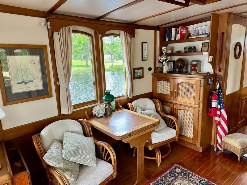 Slide: The Image of Cozy 1989 Pilgrim Trawler interior with wooden furniture, nautical decor, and large windows overlooking water. - 38