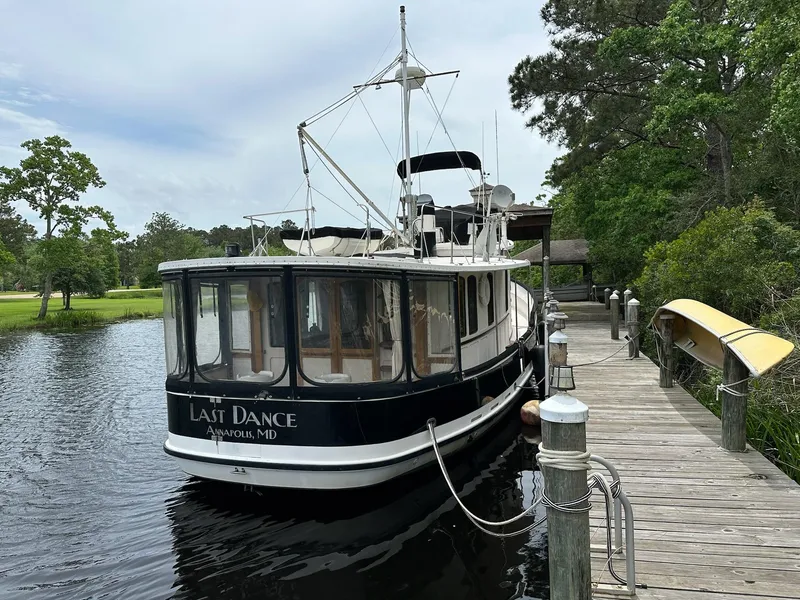 Slide: The Image of 1989 Pilgrim Trawler docked by a wooden pier, surrounded by lush greenery. - 4