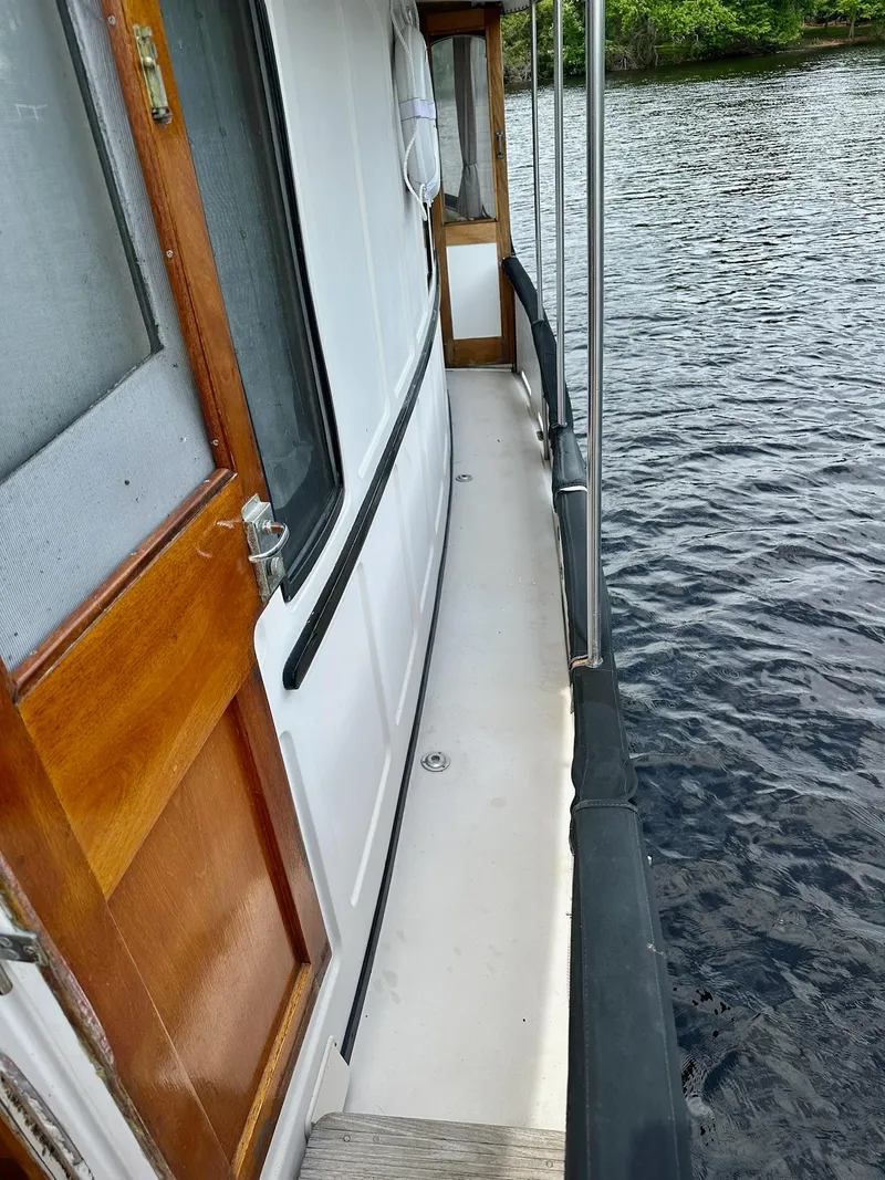 Slide: The Image of 1989 Pilgrim Trawler side deck view with wooden door, railing, and water backdrop. - 44