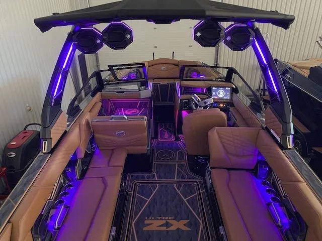 Slide: The Image of 2025 Tigé Ultré 25ZX boat interior with purple LED lighting and luxurious seating. - 2