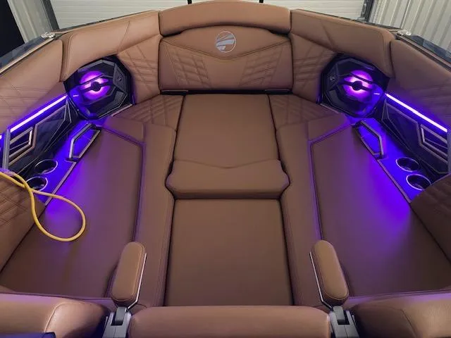 Slide: The Image of 2025 Tigé Ultré 25ZX boat interior with brown leather seats and purple LED lighting. - 5