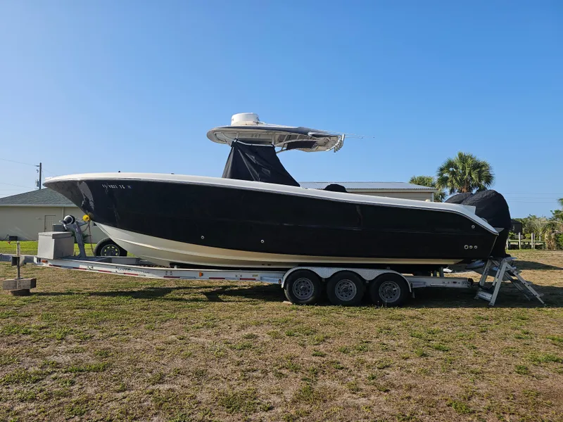 Slide: The Image of 2010 Triton 301 CC boat on trailer, black hull, clear sky background. - 0