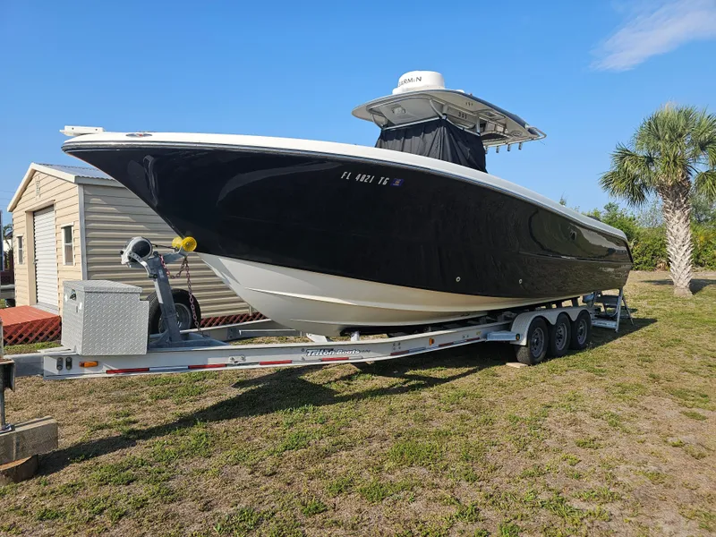 Slide: The Image of 2010 Triton 301 CC boat on trailer, parked outdoors near palm tree. - 1