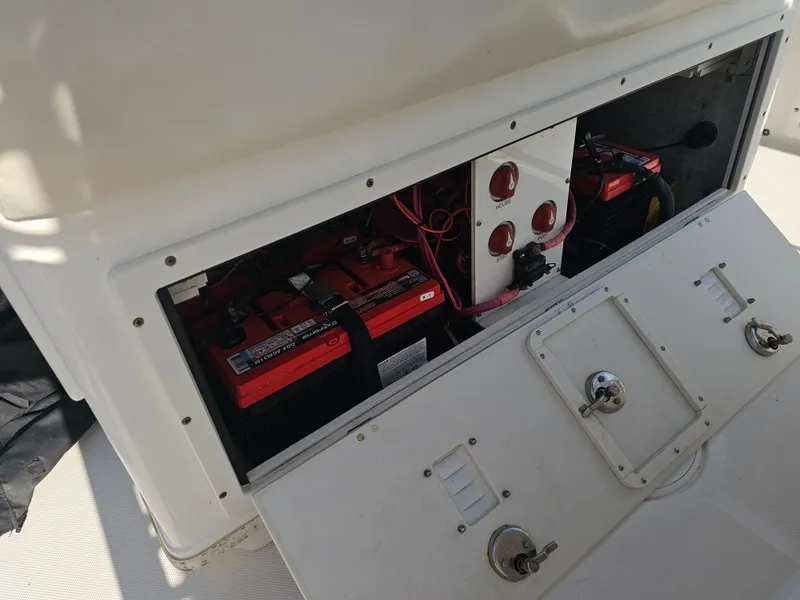 Slide: The Image of 2010 Triton 301 CC boat battery compartment with red batteries and control panel. - 20
