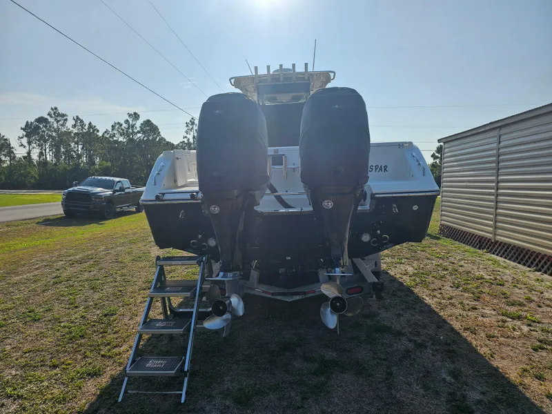 Slide: The Image of 2010 Triton 301 CC boat with dual outboard motors, parked on grass near a truck. - 3