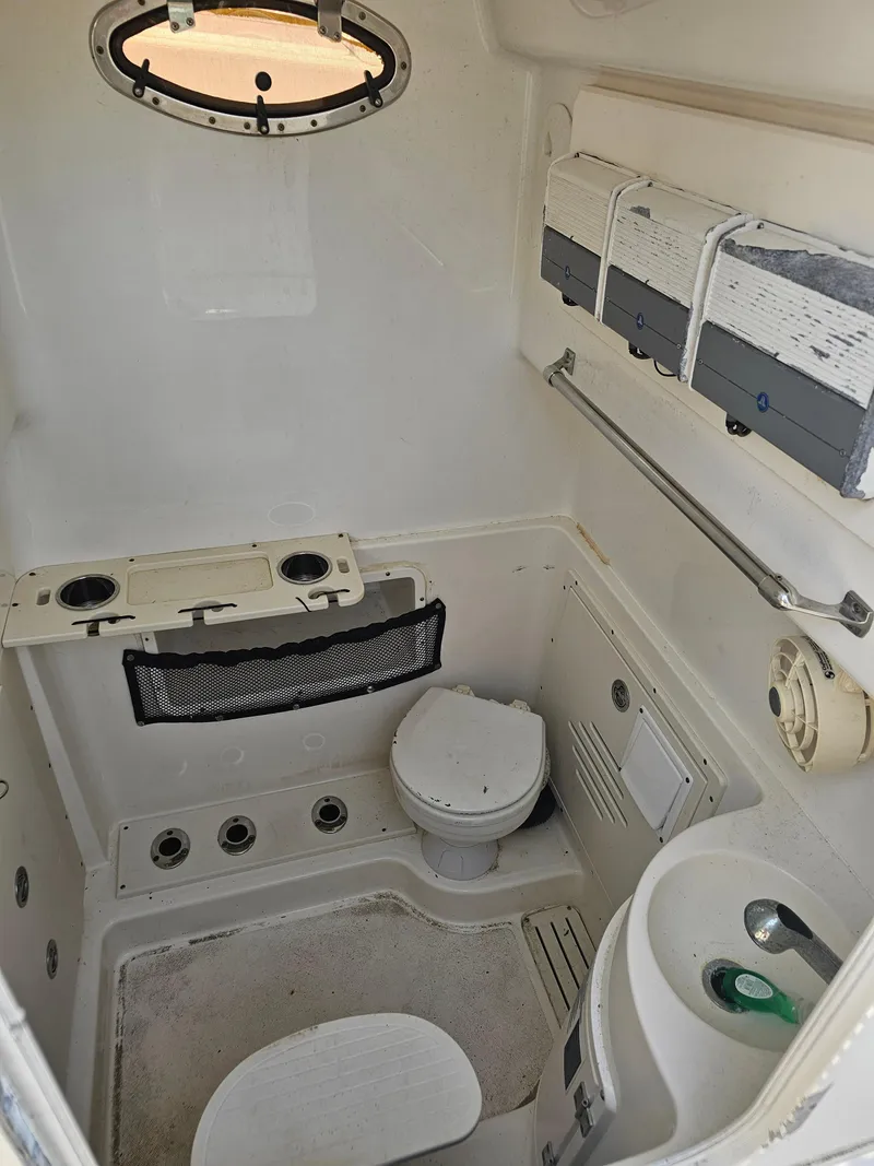 Slide: The Image of 2010 Triton 301 CC boat interior with compact bathroom and porthole window. - 43