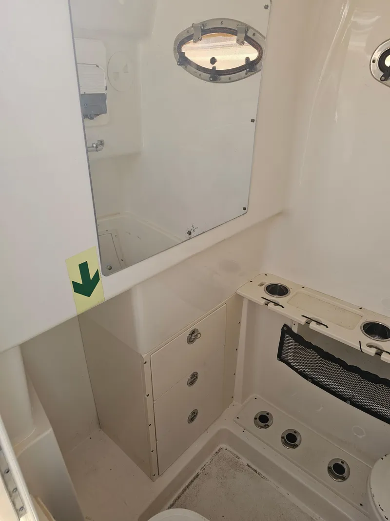 Slide: The Image of Interior of a 2010 Triton 301 CC boat, featuring storage compartments and a porthole window. - 44