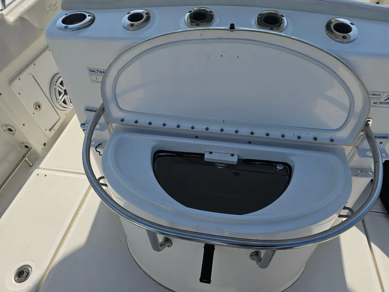 Slide: The Image of 2010 Triton 301 CC boat livewell with open lid and rod holders. - 49