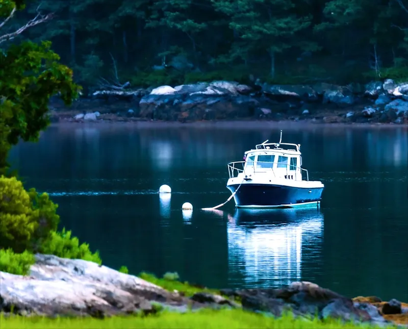 Slide: The Image of 2003 Albin 28 TE Flush Deck boat on calm lake with forested shoreline. - 1