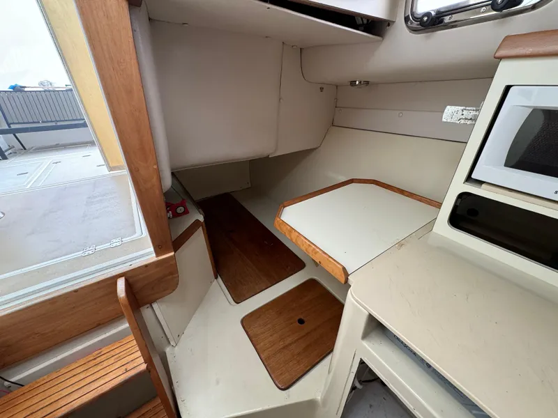 Slide: The Image of Interior of 2003 Albin 28 TE Flush Deck boat, featuring compact cabin space and wooden accents. - 27