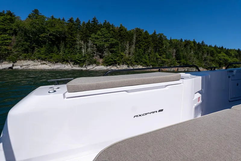 Slide: The Image of 2025 Axopar 45 boat with seating, cruising near a forested shoreline. - 28