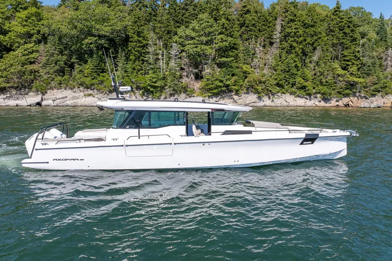 Slide: The Image of 2025 Axopar 45 boat cruising on a scenic lake with forested shoreline. - 5