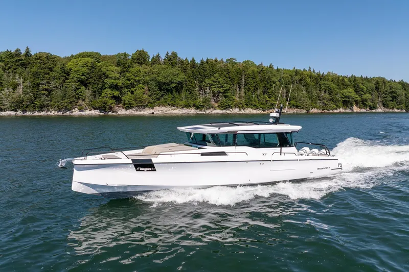 Slide: The Image of 2025 Axopar 45 boat cruising on a scenic lake with forested shoreline. - 7