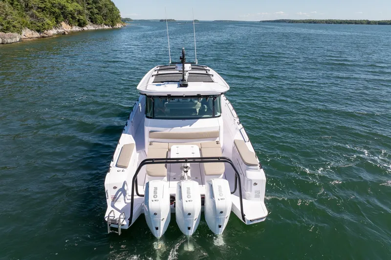 Slide: The Image of 2025 Axopar 45 boat with seating area, cruising near a forested shoreline. - 31