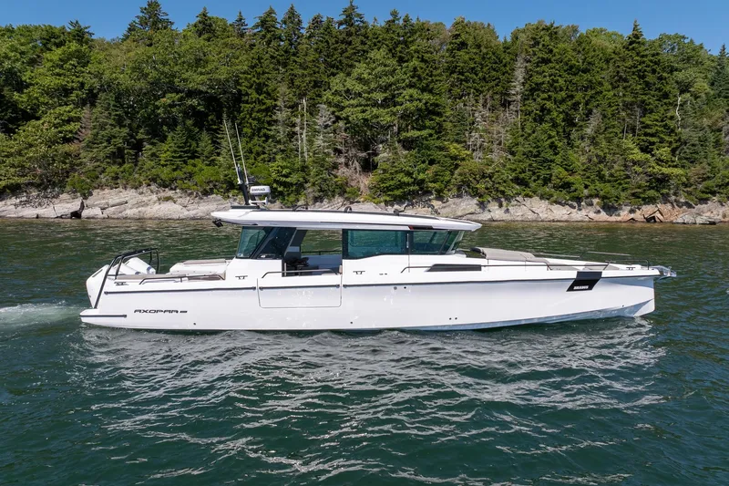 Slide: The Image of 2025 Axopar 45 boat cruising on a scenic lake with forested shoreline. - 6
