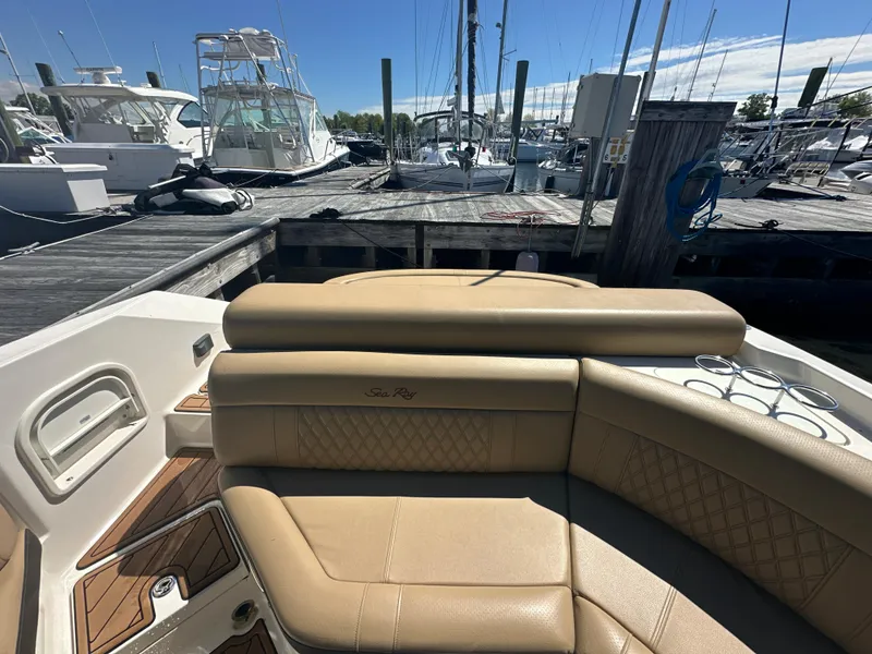 Slide: The Image of 2019 Sea Ray SLX 280 boat interior with tan seating at marina. - 39