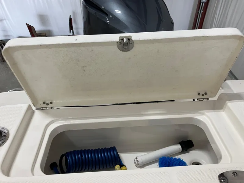 Slide: The Image of Open storage compartment on 2021 Robalo R242 Center Console boat with cleaning supplies. - 33