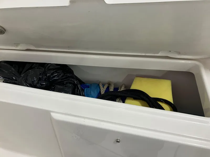 Slide: The Image of Storage compartment in a 2021 Robalo R242 Center Console boat with various items. - 42