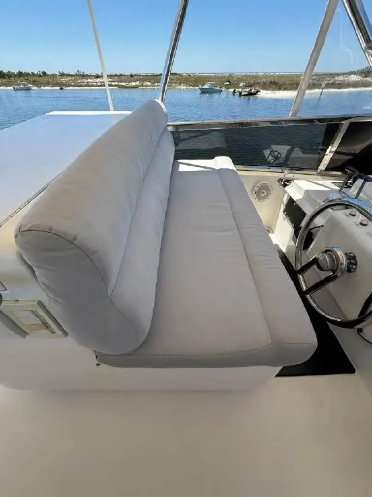 Slide: The Image of 2000 Horizon E 65 boat interior with cushioned seating and steering wheel, overlooking calm waters. - 14