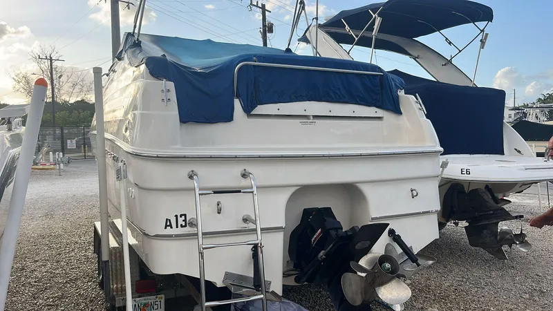 Slide: The Image of 2000 Regal Commodore 2460 boat with blue cover, parked on gravel. - 2