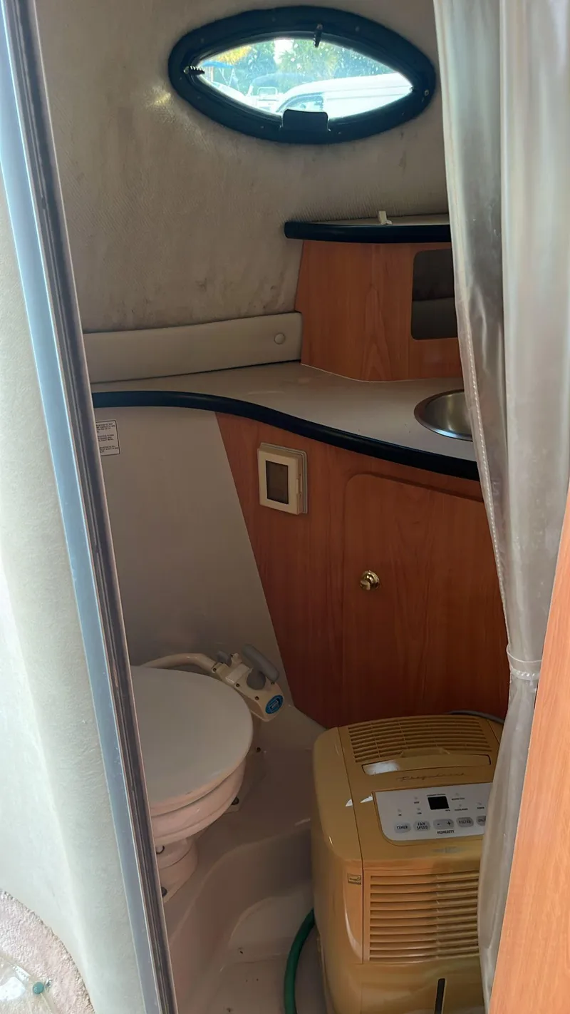 Slide: The Image of 2000 Regal Commodore 2460 boat bathroom with sink, toilet, and porthole window. - 8